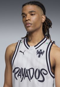 Grå mesh basketballtrøje med sorte accenter, prydet med fed "RAYADOS" tekst og et holdlogo. Ribbede krave og ærmegab.