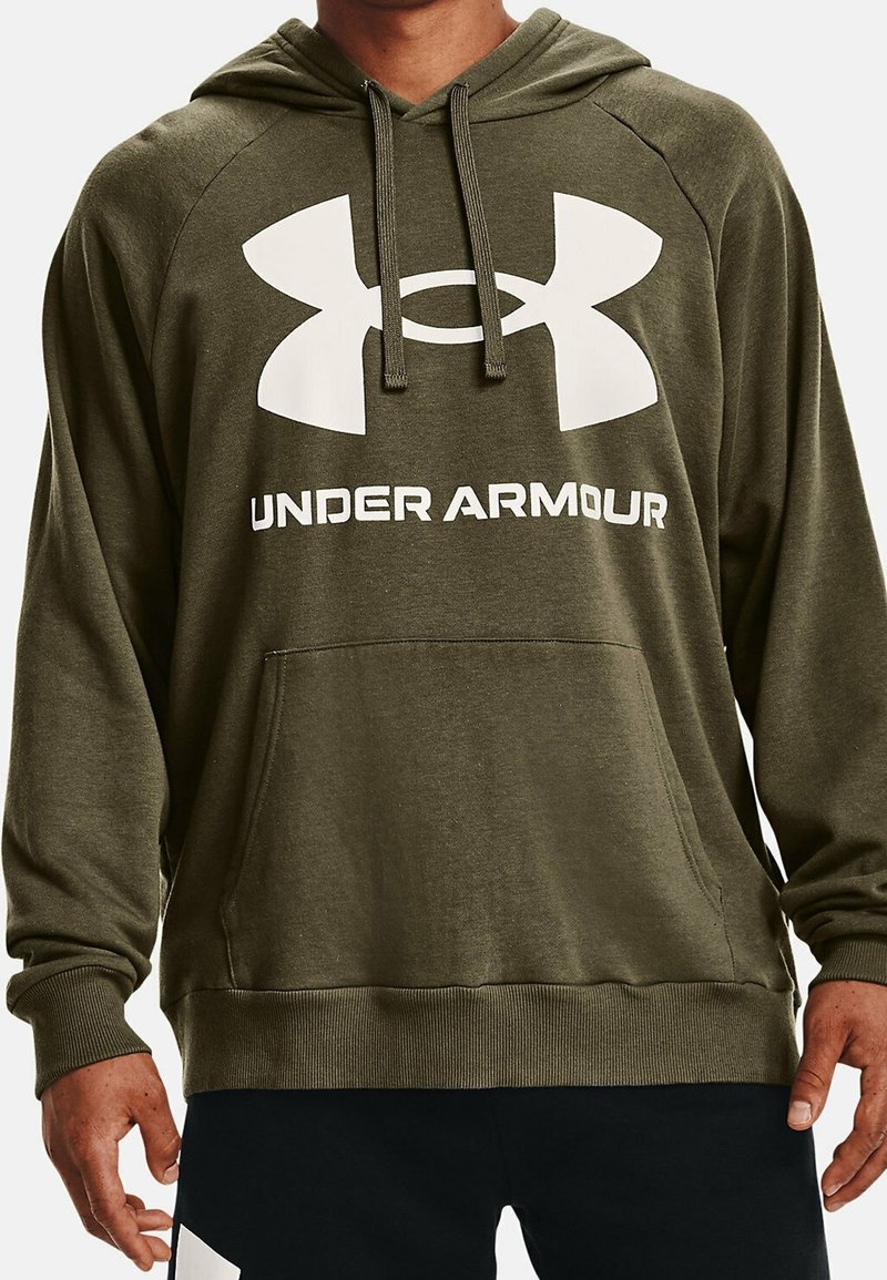 Uomo che indossa un felpa olive verde di Under Armour con grande logo bianco e tasca frontale, abbinata a pantaloni neri con dettagli bianchi.