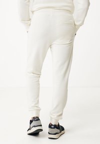 Krämfärgade sweatpants med en smal passform och elastisk midja. Utrustad med en bakficka och ribbade manschetter, tillsammans med mörka sneakers.