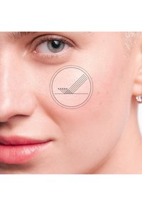 Nahaufnahme einer glatten, hellen Haut mit einem dezenten Schimmer. Auf der Wange ist ein rundes Logo mit fünf parallelen Linien überlagert.