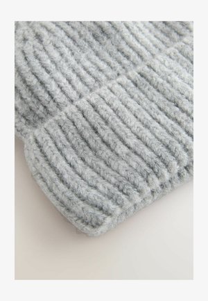 Siva pletena kapa iz mehkega volne. Ima rebrasto teksturo z zavihkom na dnu. Topla in udobna zasnova.
