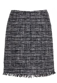 Knälång kjol gjord av svart och vit texturerad tyg med ett vävt mönster och fransdetaljer i nederkanten. Har ett åtsittande midjeband.