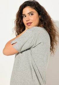 Grijze T-shirt met korte mouwen, beschikt over een losse pasvorm, zijsplitsingen en een zachte textuur, ontworpen voor comfort en casual gebruik.