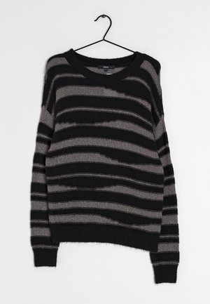 Pull ras du cou à rayures noires et grises avec des rayures horizontales irrégulières, suspendu à un cintre noir sur un fond blanc.