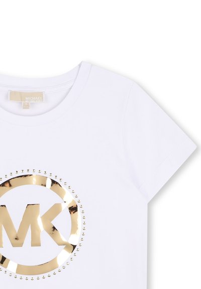 T-shirt blanc à manches courtes avec logo MK métallique doré entouré de petits clous dorés, col rond, et étiquette de la marque à l'intérieur du col.