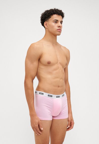 Boxer briefs rosa in cotone con un design aderente e una cintura con logo nero, indossati da un modello su uno sfondo semplice.