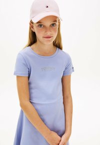 Liliowa sukienka z krótkim rękawem, dopasowaną górą i rozkloszowanym dołem. Zawiera logo "TOMMY HILFIGER", wykonana z miękkiej bawełny. Różowa czapka z akcentem logo.