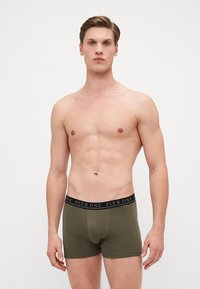 Olivgrüne Boxershorts mit einem schwarzen, markierten Bund. Sie bieten eine enganliegende Passform und eine weiche Textur. Keine Muster oder zusätzlichen Details erkennbar.