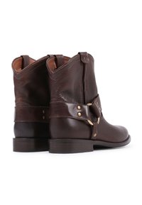 Dark brown leather ankle boots with a textured finish, featuring a strap with brass accents and a low wooden heel.