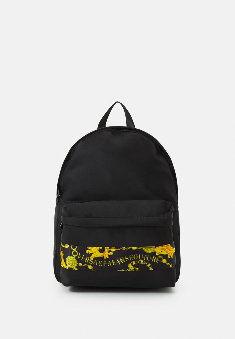 Mochila negra con forma redondeada, bolsillo frontal con cremallera que presenta un gráfico decorativo amarillo y un logo, fabricada con un material duradero.
