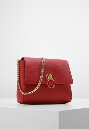 Rød læderhåndtaske med guld kædestrop og guldlås, vist på en hvid piedestal mod en lysegrå baggrund.