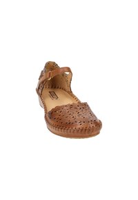 Chaussure plate en cuir marron avec un motif floral découpé et une bride à la cheville, bout rond et finition cousue sur le bord.