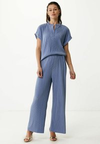 Niebieski, plisowany dwuelementowy zestaw składający się z krótkiego rękawa bluzki z półguzikowym zapięciem oraz szerokich spodni. Gładka tekstura i luźny krój.