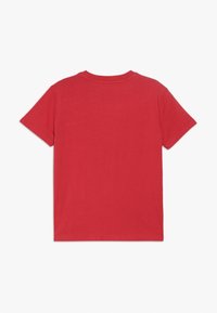 Camiseta de algodón roja con cuello redondo y mangas cortas. La parte trasera es lisa, sin logos ni adornos visibles.