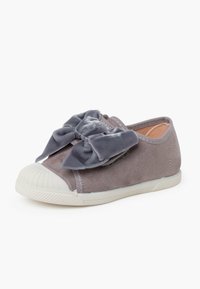 Scarpa slip-on in suede grigio con un grande fiocco in tessuto grigio sulla parte anteriore, punta in gomma bianca e suola bianca testurizzata.