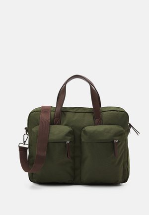 Sac en tissu vert avec deux poches avant, accents en cuir marron, double poignée supérieure et une bandoulière amovible. Fermetures éclair.