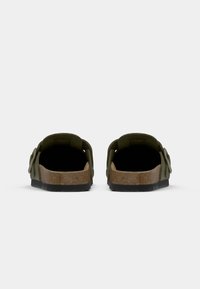 Olijfgroene sandalen met een kurken voetbed, open achterkant en verstelbare banden. De zool is textuur voor grip, wat comfort en ondersteuning biedt.