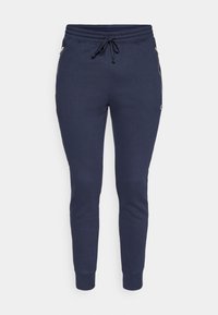 Pantalones jogger azul marino hechos de tela suave, con cintura ajustable con cordón y bolsillos laterales con cremallera, con puños acanalados en los tobillos.