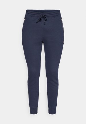 Pantalones jogger azul marino hechos de tela suave, con cintura ajustable con cordón y bolsillos laterales con cremallera, con puños acanalados en los tobillos.