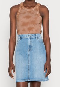 Brun batikryggad linne med rund halsringning, ihopparat med en ljusblå denimkjol med rak silhuett och knäppning fram.