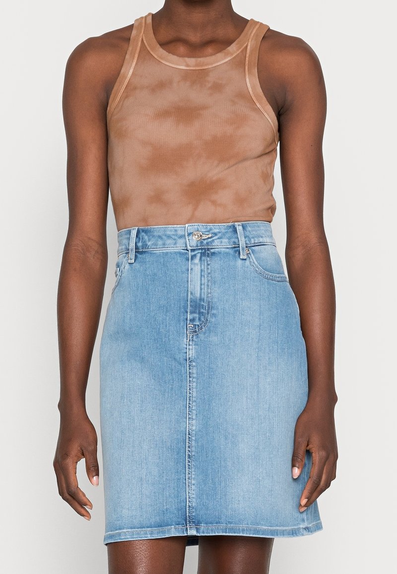 Brun batikryggad linne med rund halsringning, ihopparat med en ljusblå denimkjol med rak silhuett och knäppning fram.