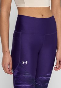 Leggings viola con vita alta, tessuto strutturato e design gradiente. Presentano un logo sulla coscia sinistra e tasche laterali.