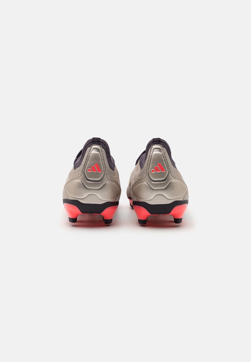 Crampons de football Adidas avec une tige grise et noire, des accents roses et des crampons moulés. Présente une texture lisse et brillante ainsi qu'un design courbé.