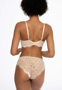 Zestaw bielizny koronkowej w kolorze nude z kwiatowymi wzorami, falistymi krawędziami i regulowanymi ramiączkami. Widok z tyłu ukazuje misterny detal koronki oraz zapięcie na haczyk.