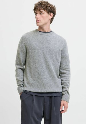 Grijze crewneck trui van fijn gebreid materiaal, met geribbelde manchetten en zoom, gecombineerd met donkere broek. Eenvoudig ontwerp met een losse pasvorm.