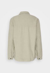 Jasna khaki koszula-kurtka z sztruksu z kołnierzem, długimi rękawami i mankietami na guziki. Charakteryzuje się prążkowaną fakturą i detalem tylnego karczka.