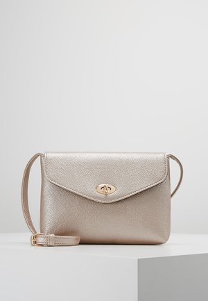 Kleine metalen beige crossbodytas met verstelbare riem en goudkleurige draaisluiting op de voorklep.