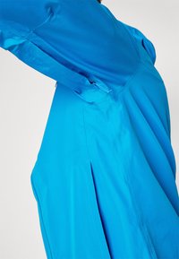 Blå kjole med en strukturert design, som har sidel pleats og glatt tekstur. Laget av lett stoff, har den en tilpasset look.