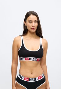 Conjunto de lingerie preto com um soutien desportivo com acabamento branco e uma cintura larga com padrão arrojado. Material em algodão, design simples e bordas sem costuras.