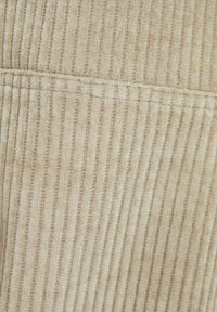 Beige corduroy stof met verticale geribde textuur. Kenmerkt zich door fijne stiksels en een zachte, fluweelachtige afwerking; subtiele glans op het oppervlak.