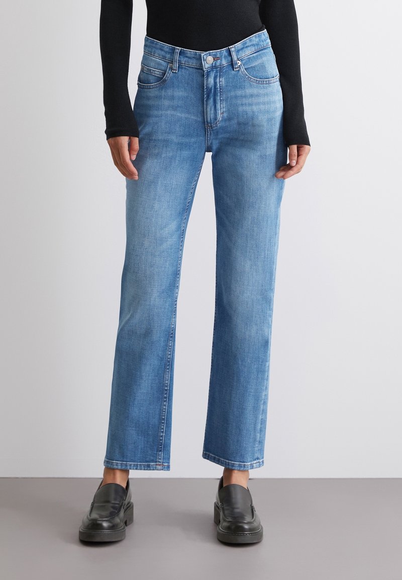 Jean droit bleu clair en denim, avec un design classique à cinq poches et un léger effet d'usure à l'avant.