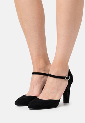 Escarpins noirs en daim avec un bout arrondi et une bride de cheville dotée d'une boucle en argent, conçus avec une finition texturée.