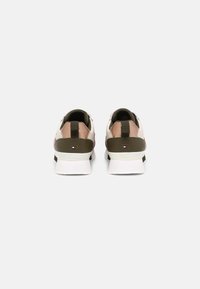 Par de zapatillas beige, rosa y verde oliva con suelas blancas, vistas desde la parte trasera, con un pequeño logo rectangular en cada talón.