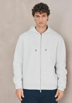 Hellgraue Kapuzenjacke mit durchgehendem Reißverschluss, strukturiertem Stoff, Kordelzügen und gerippten Bündchen. Verfügt über eine reguläre Passform und eine Kängurutasche.