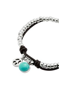 Pulsera de cuentas plateadas y cuero con un detalle en turquesa y un colgante con símbolo de la paz, con una textura suave y formas redondeadas.