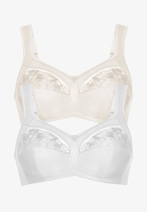 Woman standing barefoot wearing a white bra and matching high-waist panties with lace details on a plain background.