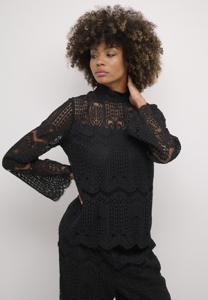 Black lace blouse with long sleeves and a high neck. Features intricate patterns and scalloped edges. Texture appears delicate and layered.