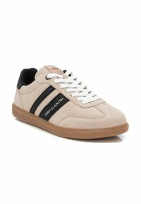 Sneaker in suede beige con strisce nere, lacci bianchi e suola in gomma naturale. Caratterizzata da un logo sul lato e colletto imbottito. Design atletico classico.