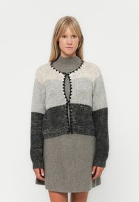 Πλεκτό cardigan με κλίμακα από ανοιχτό γκρι έως σκούρο γκρι, που διαθέτει στρογγυλή λαιμόκοψη, κλείσιμο με κουμπί και αντίθετο μαύρο περιθώριο στις άκρες.