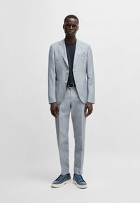 Ljusblå rutig kavaj och byxor, parat med en marinblå t-shirt och blå mockaskor. Har två knappar och framfickor.