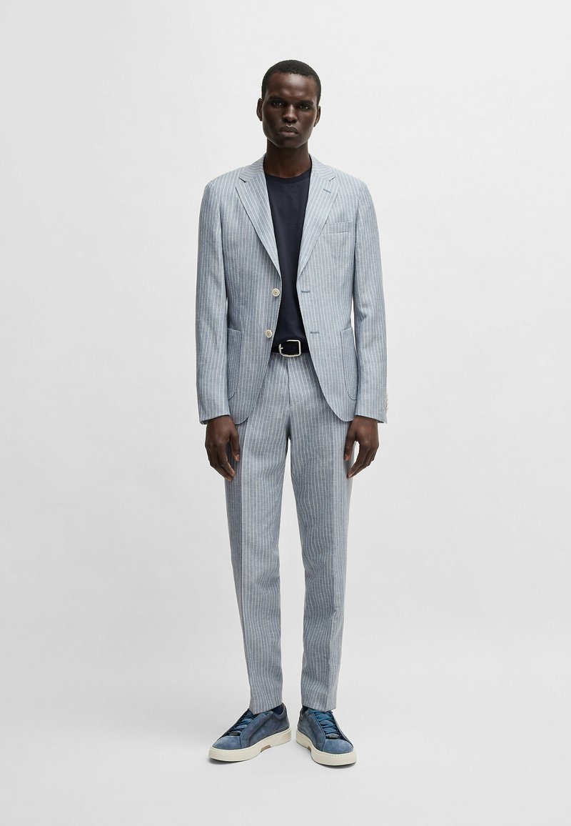 Ljusblå rutig kavaj och byxor, parat med en marinblå t-shirt och blå mockaskor. Har två knappar och framfickor.