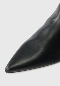 Pantof alb din piele cu toc înalt, cu vârful ascuțit, textură netedă și fără modele sau detalii de hardware vizibile.