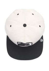 White and black cap with a flat brim, fabric texture, circular vents, and a bear graphic patch on the front. Black underside of the brim.
