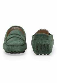 Grüne Wildleder-Loafer mit gesteppten Details, niedrigem Profil und strukturierten Gummisohlen mit runden Noppen für Grip.