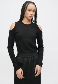 Bluză neagră cu mânecă lungă și decupaje la umeri, realizată din țesătură tip rib. Are decolteu rotund și croială mulată.