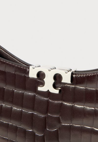 Σκούρο καφέ δερμάτινη τσάντα με υφή από κροκόδειλο και λαμπερό ασημένιο κούμπωμα διπλού Τ σε απλό φόντο.